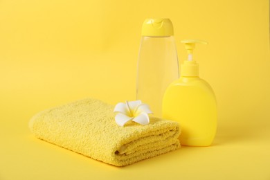 Photo of Fresh terry towel, cosmetic products and flower on yellow background. Space for text