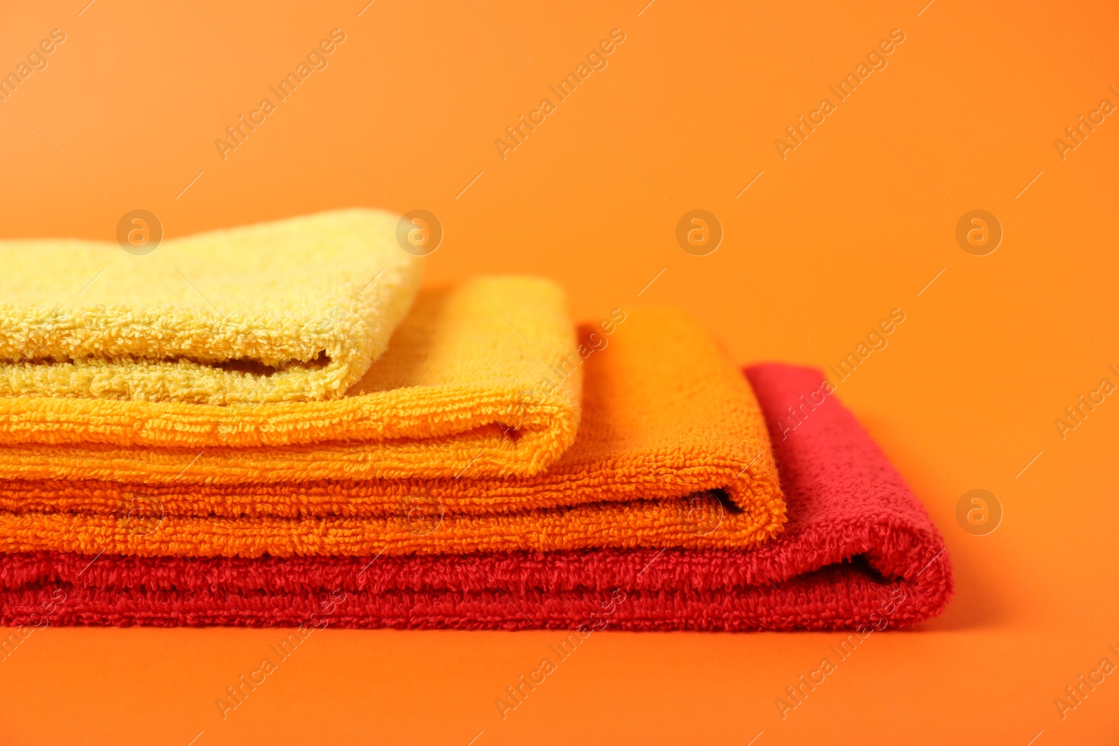 Photo of Fresh terry towels on orange background, closeup