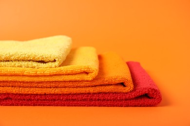 Photo of Fresh terry towels on orange background, closeup