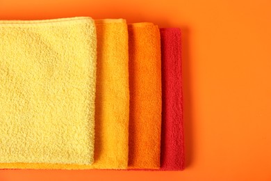 Photo of Fresh terry towels on orange background, top view