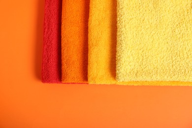 Photo of Fresh terry towels on orange background, top view