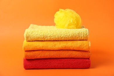 Photo of Fresh terry towels and sponge on orange background