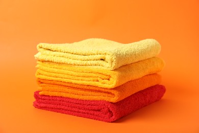Photo of Stack of fresh terry towels on orange background