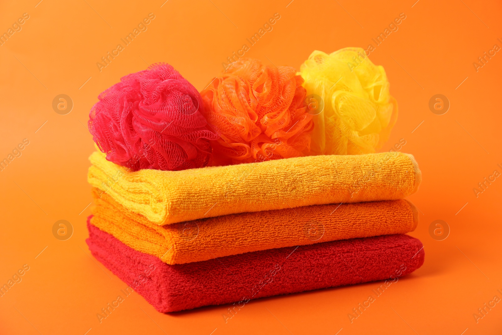 Photo of Fresh terry towels and sponges on orange background