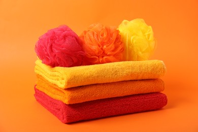 Photo of Fresh terry towels and sponges on orange background