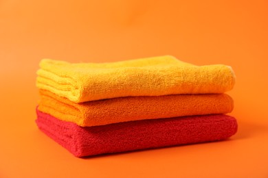 Photo of Stack of fresh terry towels on orange background