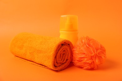 Photo of Fresh terry towel, cosmetic product and sponge on orange background