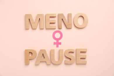 Photo of Word Menopause and female gender symbol on beige background, top view