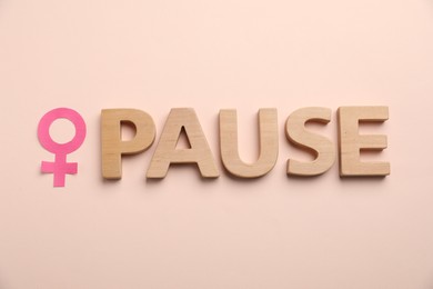 Photo of Word Pause and female gender symbol on beige background, top view