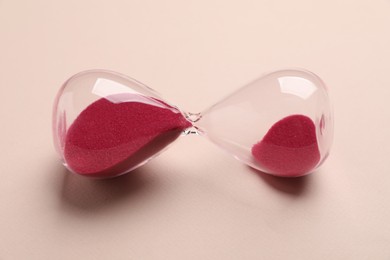 Photo of Menopause. Hourglass on beige background, closeup view