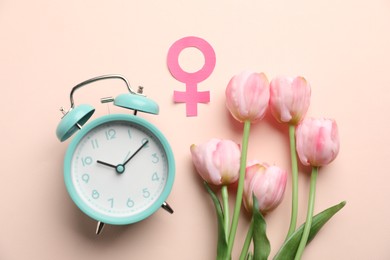 Photo of Menopause. Female gender symbol, alarm clock and tulips on beige background, flat lay