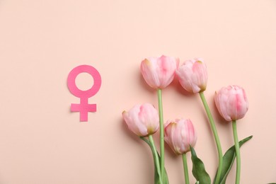 Photo of Menopause. Female gender symbol and tulips on beige background, flat lay