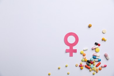 Photo of Menopause. Female gender symbol and pills on light background, flat lay. Space for text