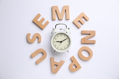 Photo of Word Menopause and alarm clock on white background, top view