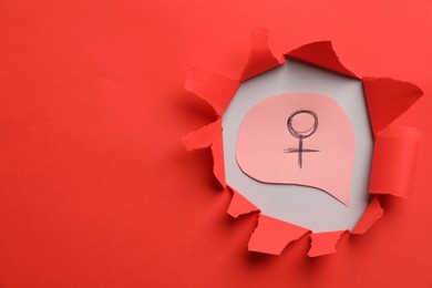 Photo of Menopause. Female gender symbol on light background, view through hole in torn red paper. Space for text