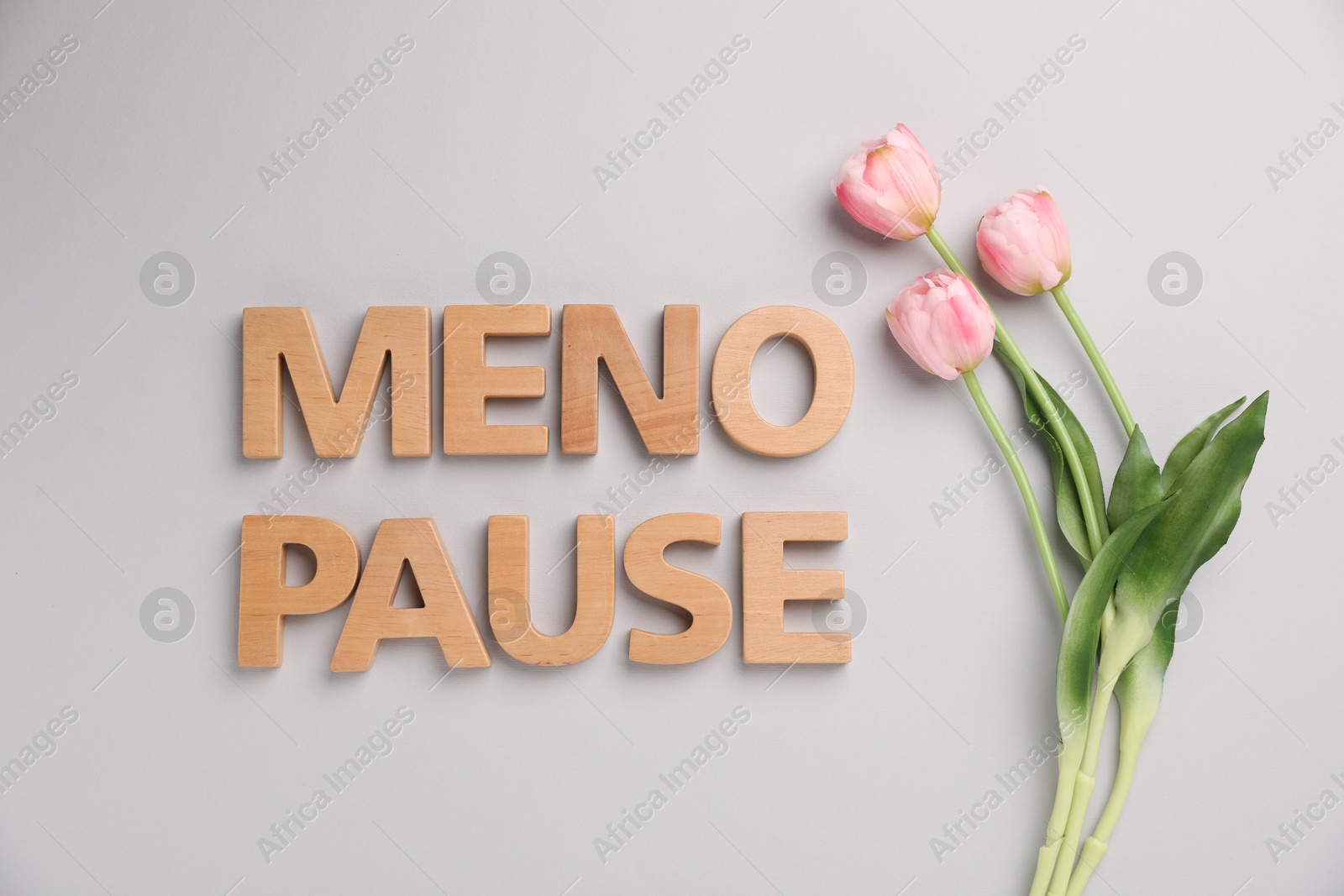 Photo of Word Menopause and tulips on light grey background, top view