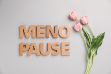Photo of Word Menopause and tulips on light grey background, top view