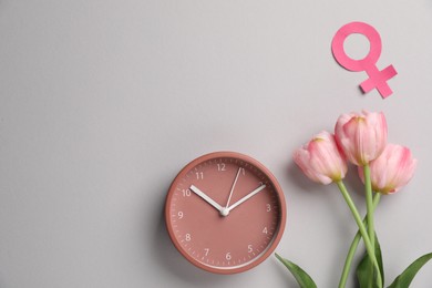 Photo of Menopause. Female gender symbol, alarm clock and tulips on light grey background, flat lay. Space for text