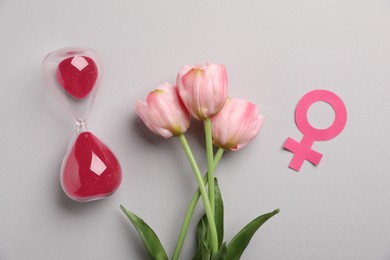 Photo of Menopause. Female gender symbol, hourglass and tulips on light grey background, flat lay
