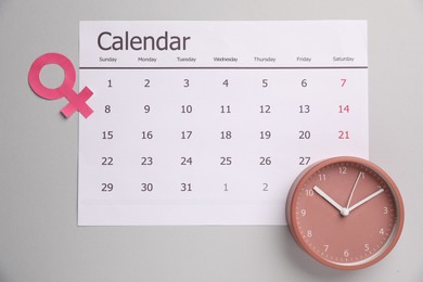Photo of Menopause. Female gender symbol, alarm clock and calendar on light grey background, flat lay