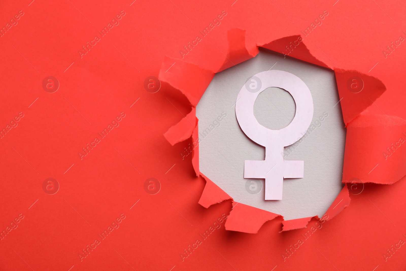 Photo of Menopause. Female gender symbol on light background, view through hole in torn red paper. Space for text
