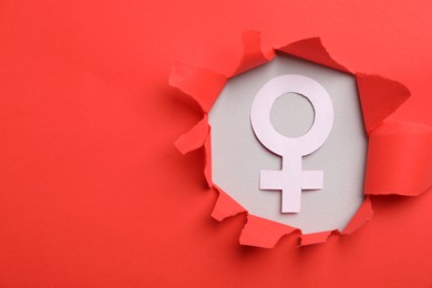 Photo of Menopause. Female gender symbol on light background, view through hole in torn red paper. Space for text