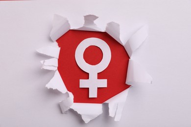 Photo of Menopause. Female gender symbol on red background, view through hole in torn white paper