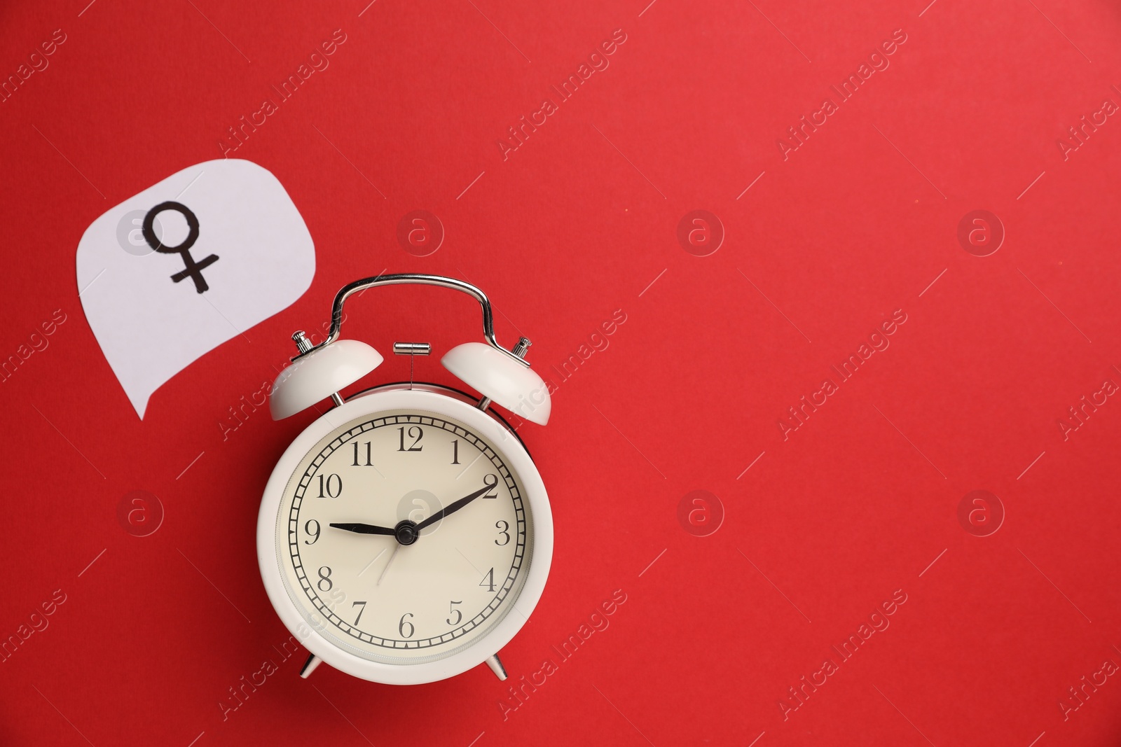Photo of Menopause. Female gender symbol and alarm clock on red background, flat lay. Space for text