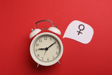 Photo of Menopause. Female gender symbol and alarm clock on red background, flat lay