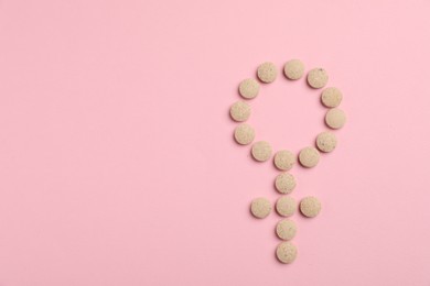 Photo of Menopause. Female gender symbol made with pills on pink background, top view. Space for text