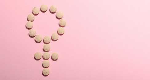 Photo of Menopause. Female gender symbol made with pills on pink background, top view. Space for text