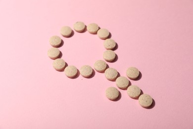 Photo of Menopause. Female gender symbol made with pills on pink background, closeup
