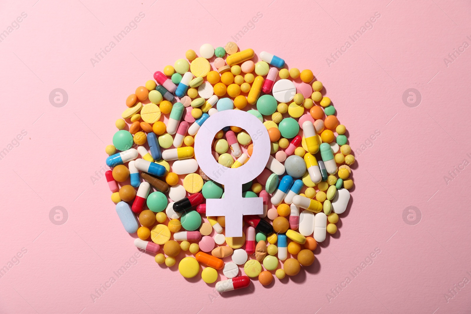 Photo of Menopause. Female gender symbol and pills on pink background, top view