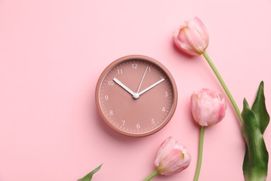 Photo of Menopause. Alarm clock and tulips on pink background, flat lay