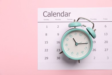 Photo of Menopause. Alarm clock and calendar on pink background, top view
