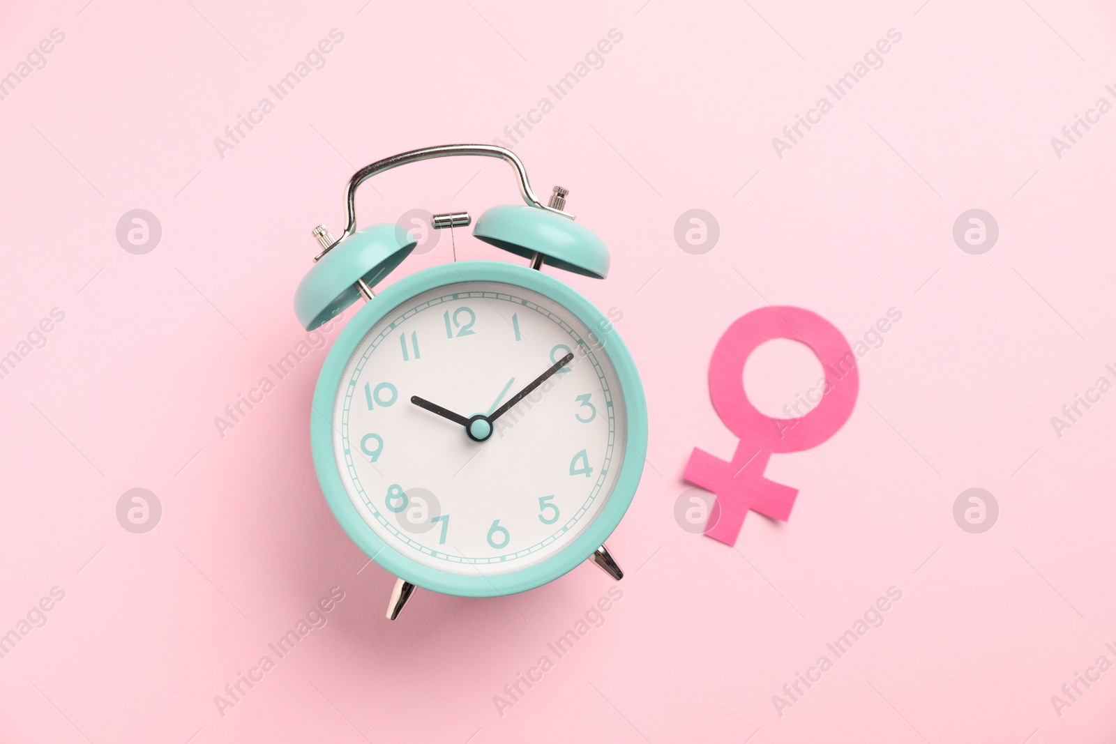Photo of Menopause. Female gender symbol and alarm clock on pink background, flat lay