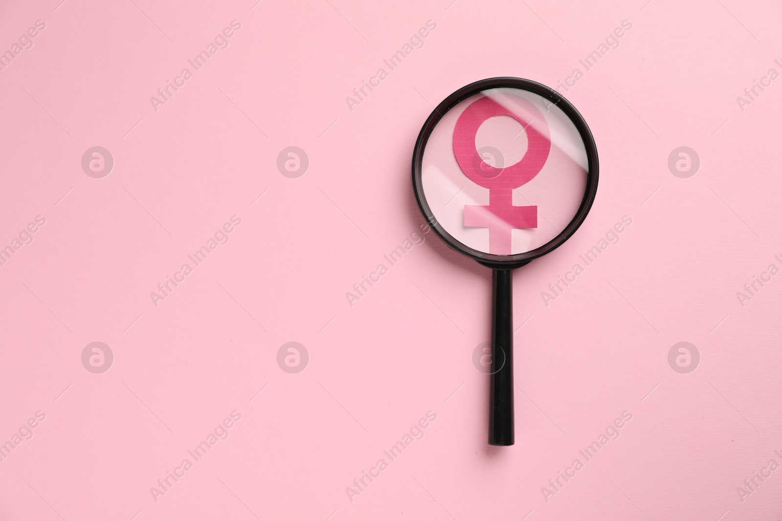 Photo of Menopause. Magnifying glass over female gender symbol on pink background, top view. Space for text