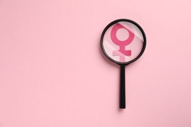 Photo of Menopause. Magnifying glass over female gender symbol on pink background, top view. Space for text