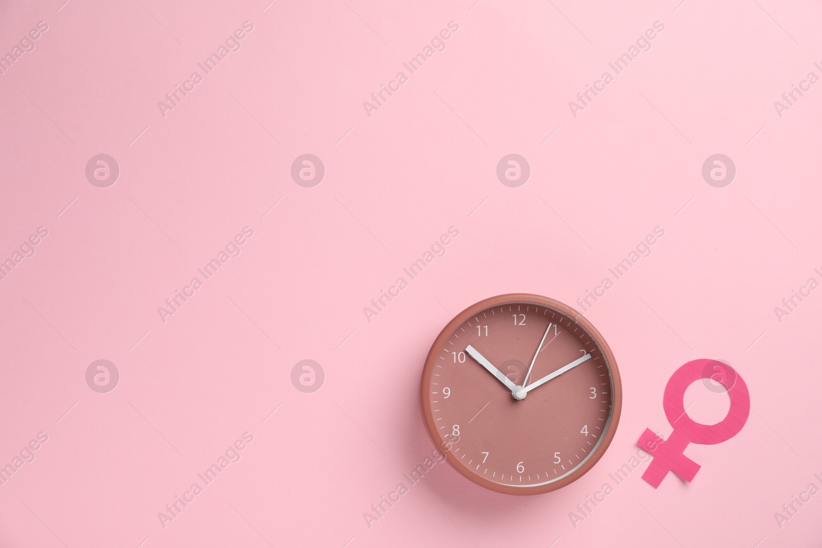 Menopause. Female gender symbol and alarm clock on pink background, flat lay. Space for text Photo of Menopause. Female gender symbol and alarm clock on pink background, flat lay. Space for text