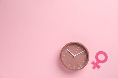 Photo of Menopause. Female gender symbol and alarm clock on pink background, flat lay. Space for text