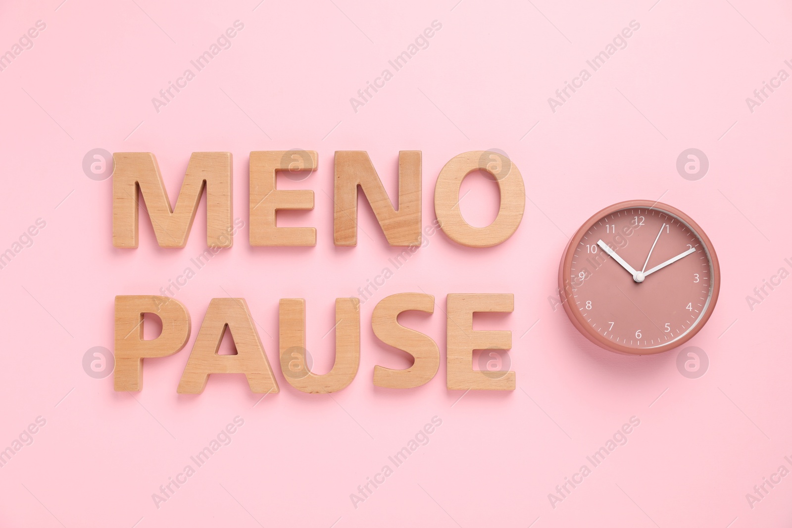 Photo of Word Menopause and alarm clock on pink background, top view