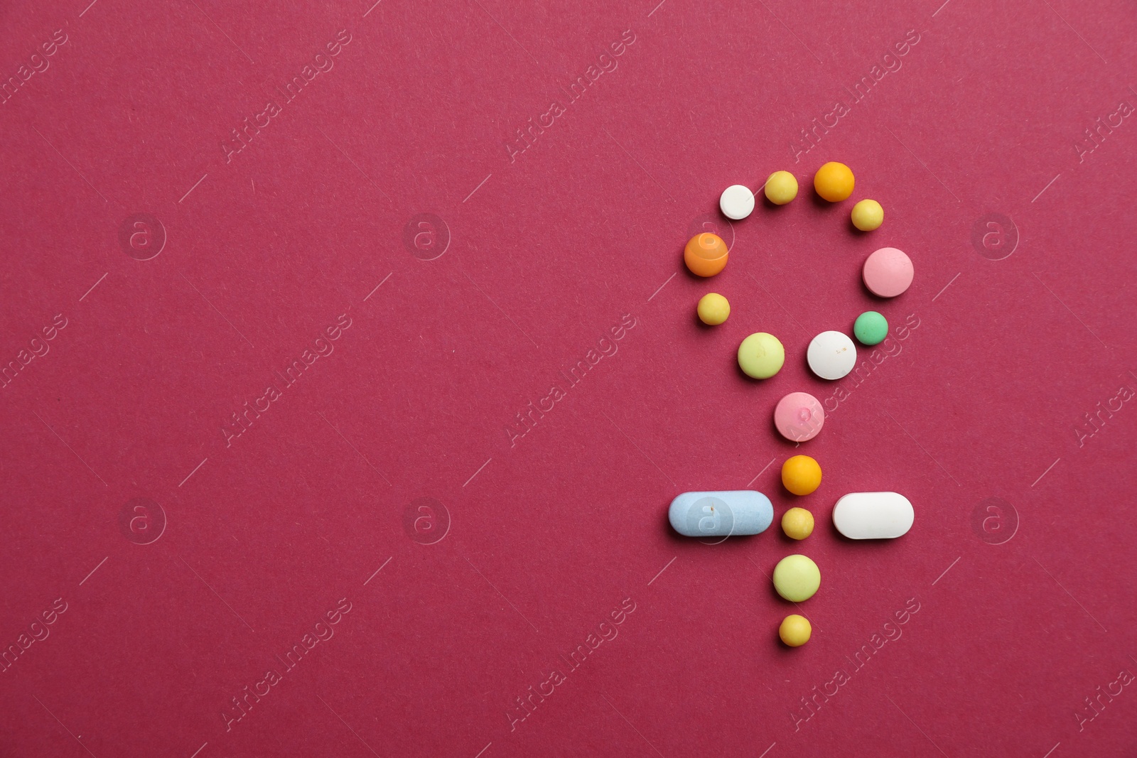 Photo of Menopause. Female gender symbol made with pills on crimson background, top view. Space for text
