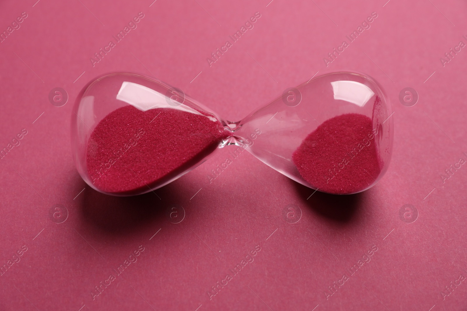 Menopause. Hourglass on crimson background, closeup view Photo of Menopause. Hourglass on crimson background, closeup view
