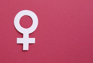 Photo of Menopause. Female gender symbol on crimson background, top view. Space for text