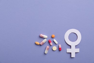Photo of Menopause. Female gender symbol and pills on violet background, flat lay. Space for text