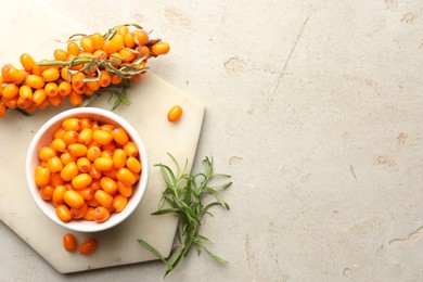 Photo of Fresh sea buckthorn berries in bowl and leaves on beige table, flat lay. Space for text