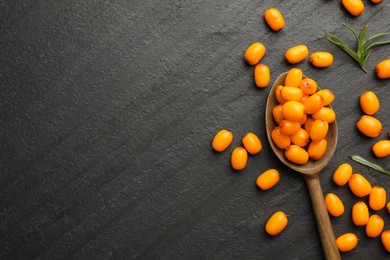 Photo of Fresh sea buckthorn berries, spoon and leaves in on black table, flat lay. Space for text