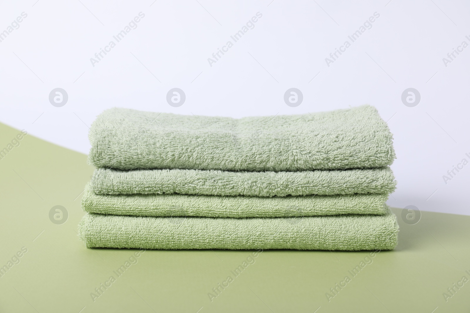 Photo of Stack of fresh terry towels on color background