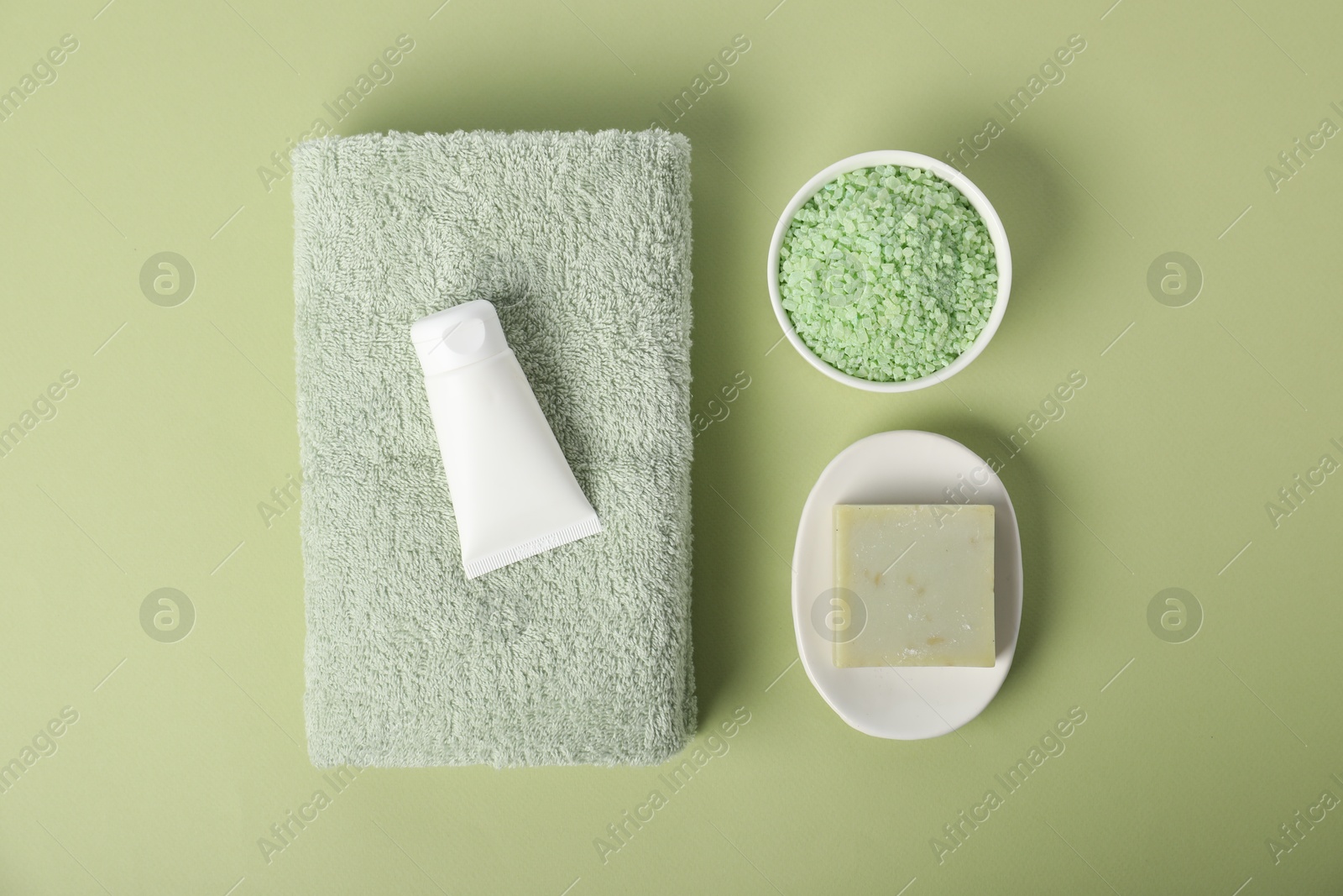 Photo of Fresh terry towel and cosmetic products on green background, flat lay