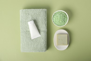 Photo of Fresh terry towel and cosmetic products on green background, flat lay